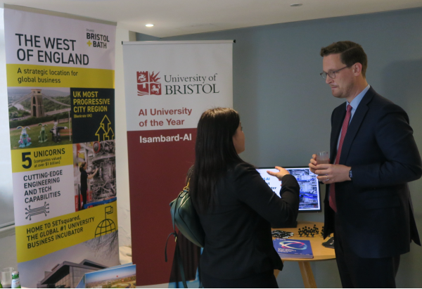 Darren Jones speaks to a woman at UKAI event in front of a University of Bristol banner